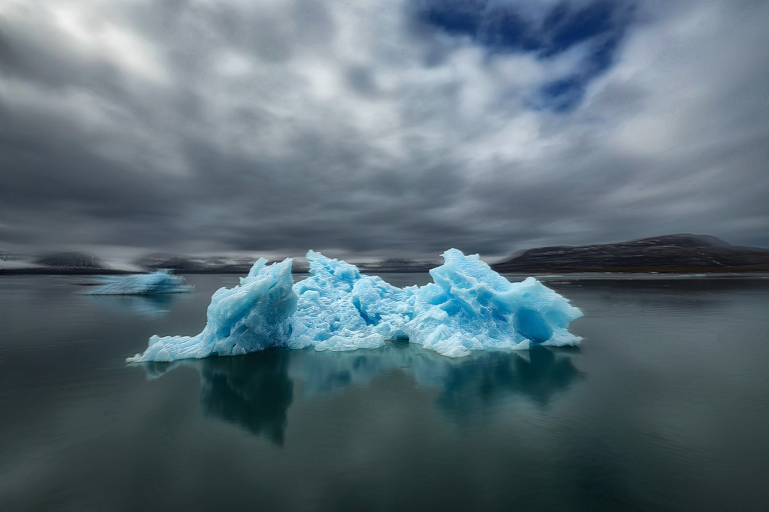 Blue iceberg in still grey water