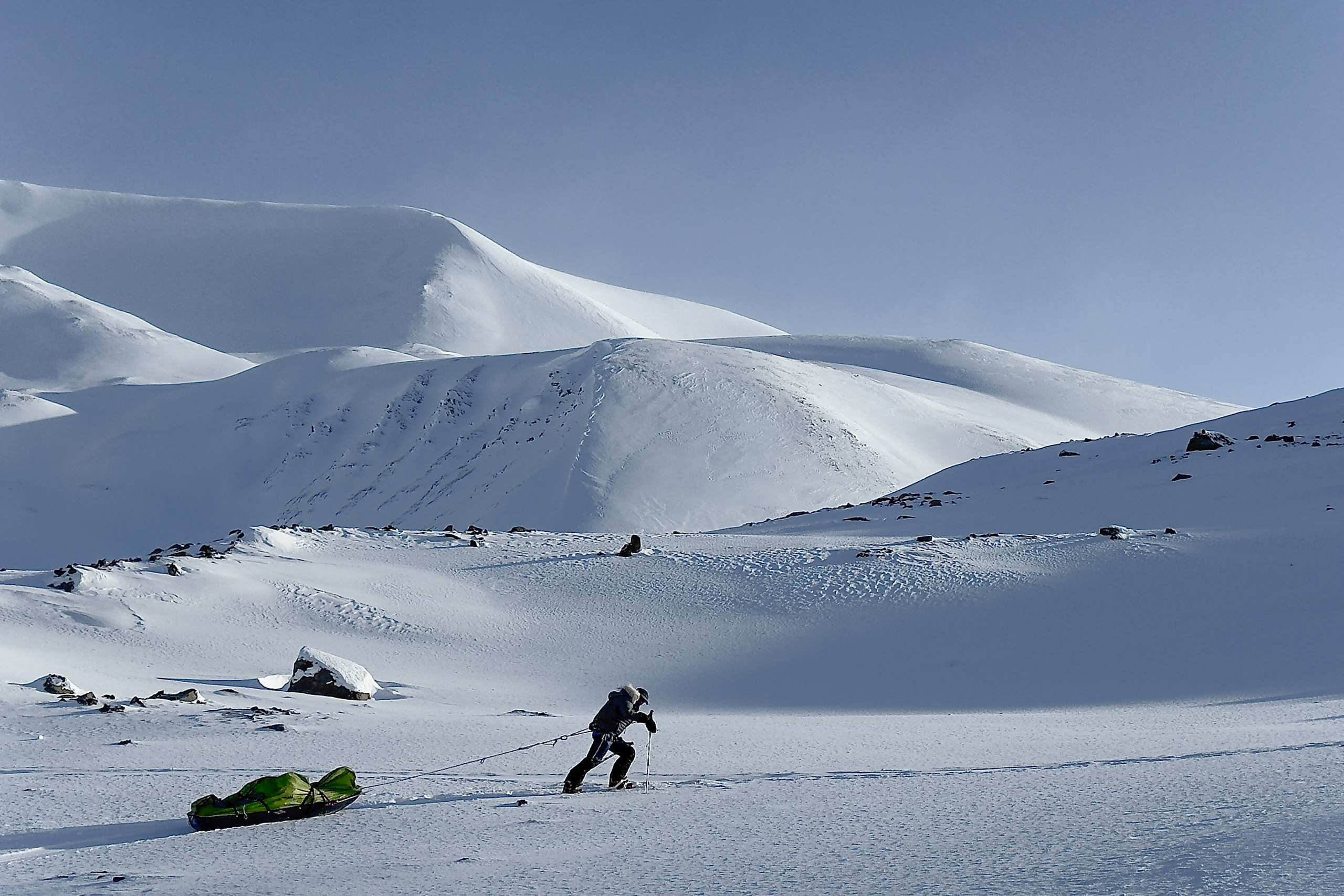 A skier hauling below the peaks